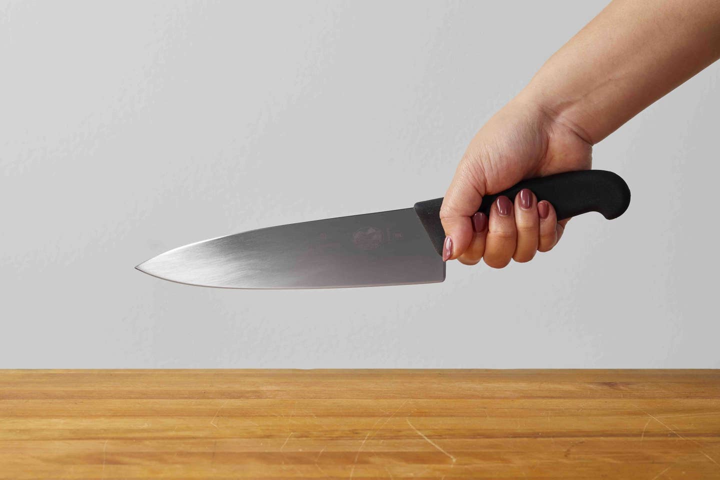 A hand holds a knife in the pinch grip