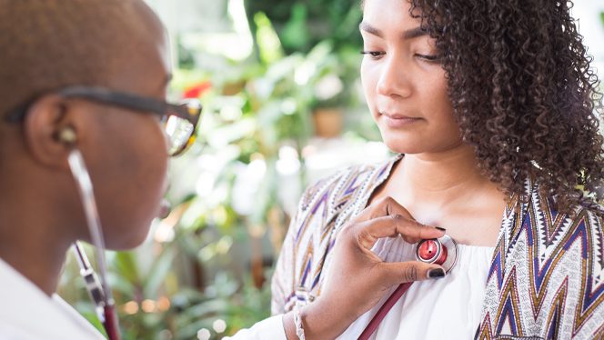 Doctor places stethoscope on woman's chest
