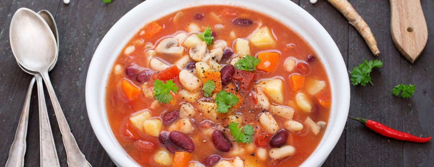 Mixed Beans and Root Vegetable Stew in a white bowl on a dark wooden table top