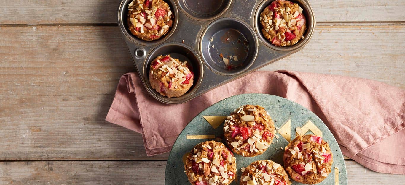 strawberry rhubarb muffins in a muffin tin and an on gray plate with a pink napkin