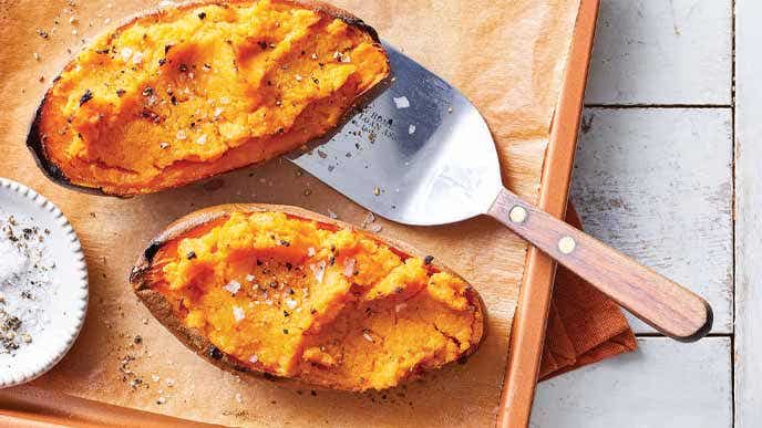 Sriracha Stuffed Sweet Potatoes on a parchment lined baking sheet with a metal spatula