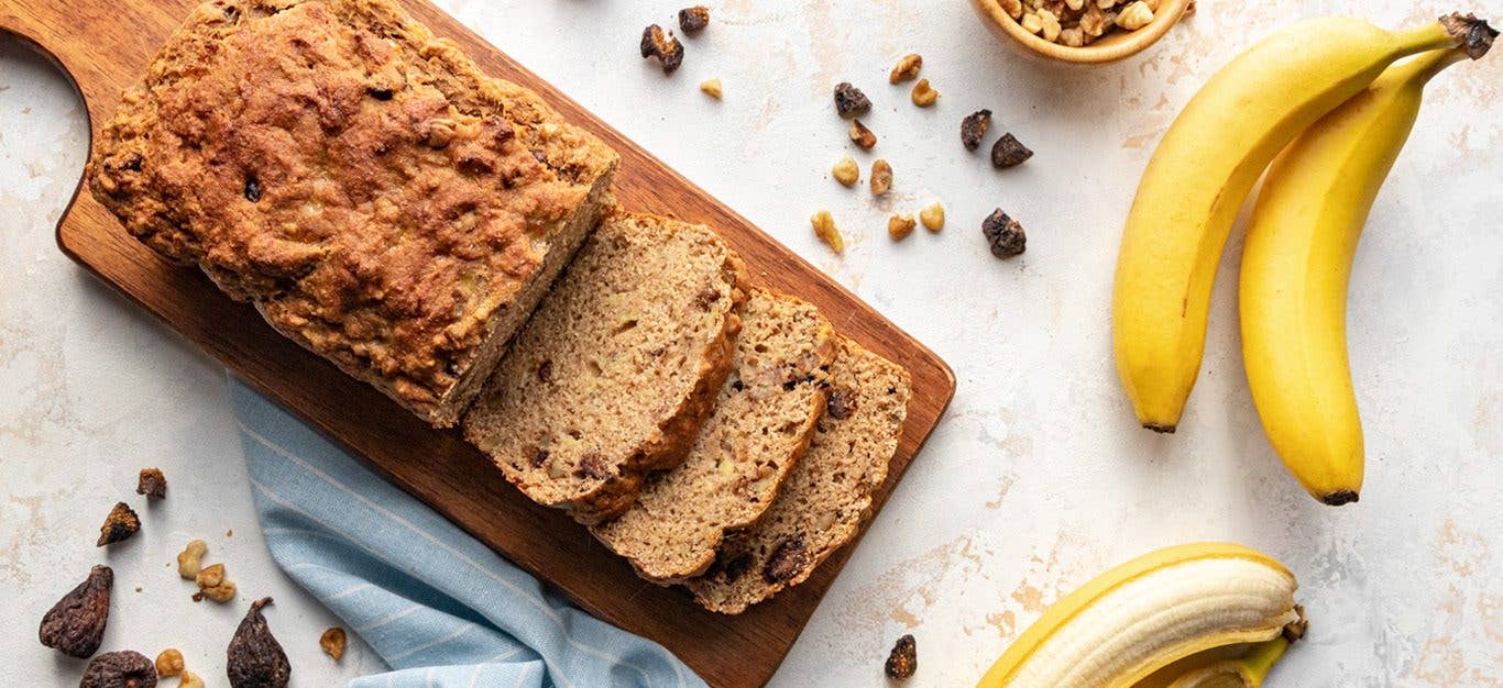 vegan banana bread sliced shown with dried figs and whole bananas