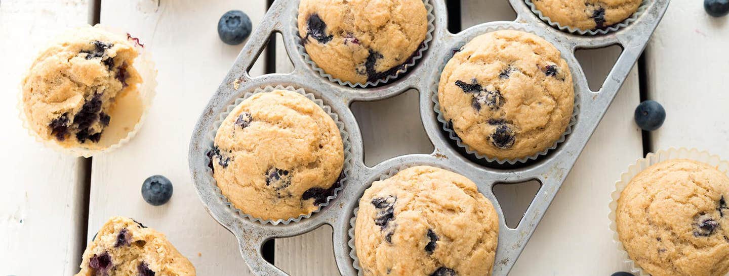 A muffin tray of Whole-Wheat Berry Muffins with three muffins to the side