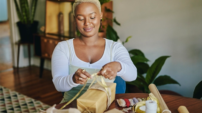 Young woman wrapping presents in living room