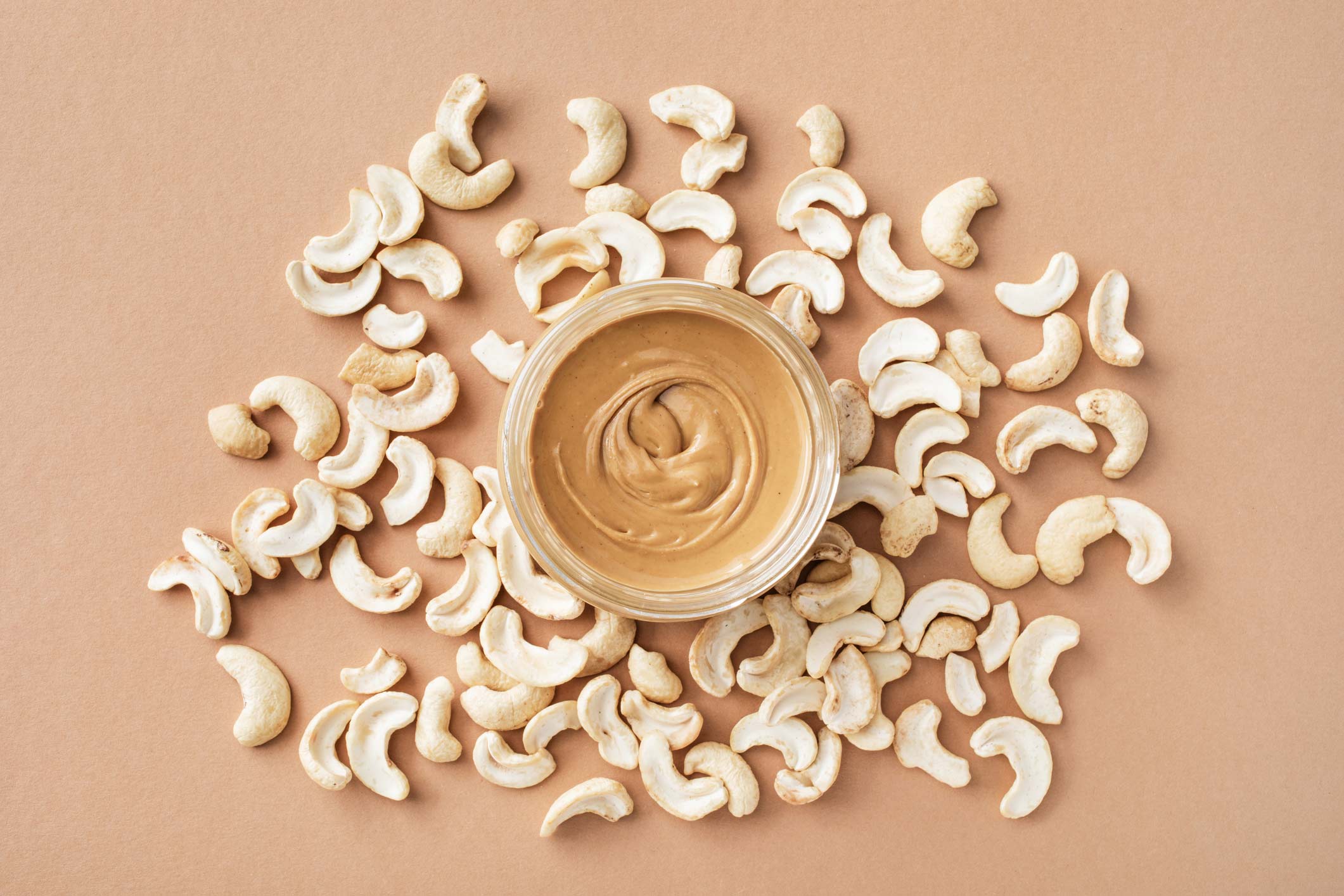 A jar of creamy cashew butter surrounded by raw cashews
