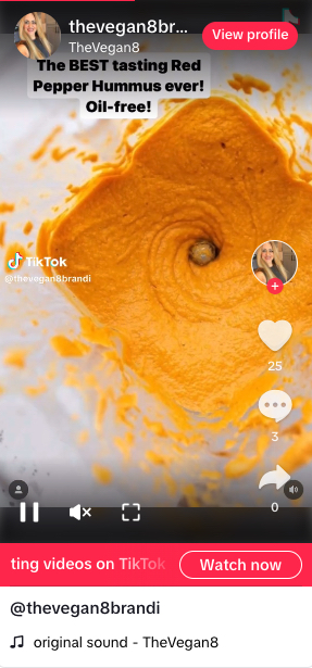 Screenshot of a TikTok video by Brandi Doming of TheVegan8 - the screenshot shows an oil-free red pepper hummus in a blender
