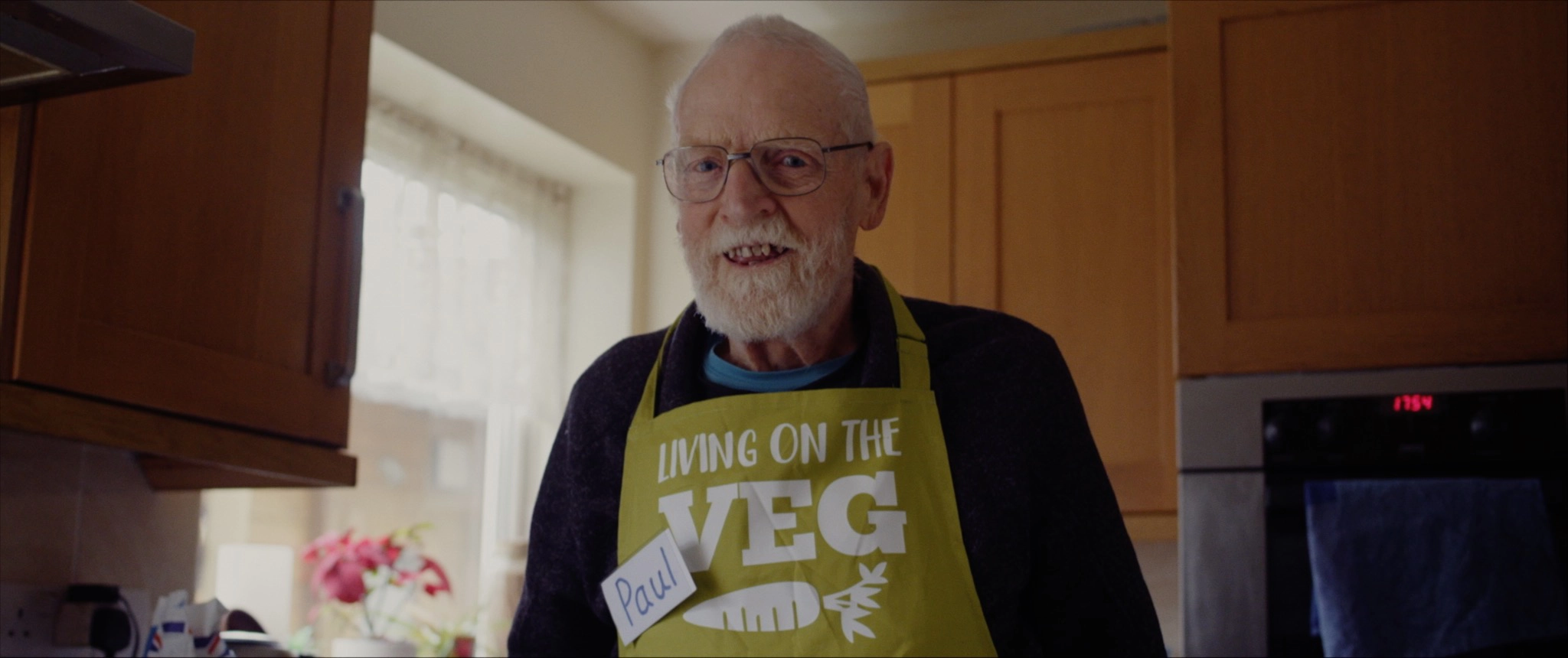 Paul Youd in his kitchen wearing an apron that says LIVING ON THE VEG