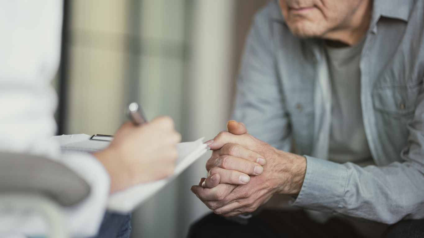 Doctor reviews lab test results with an older male patient during a medical consultation