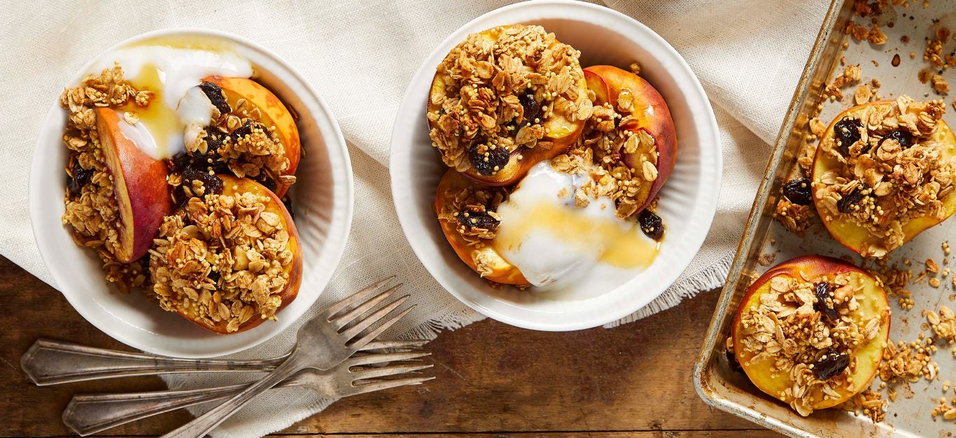 Baked Peaches with Granola Topping in white bowls on a wooden table