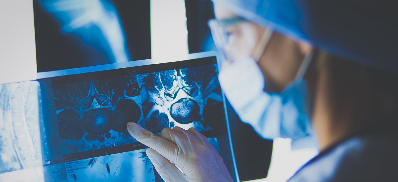 A masked doctor looks at a MRI scan