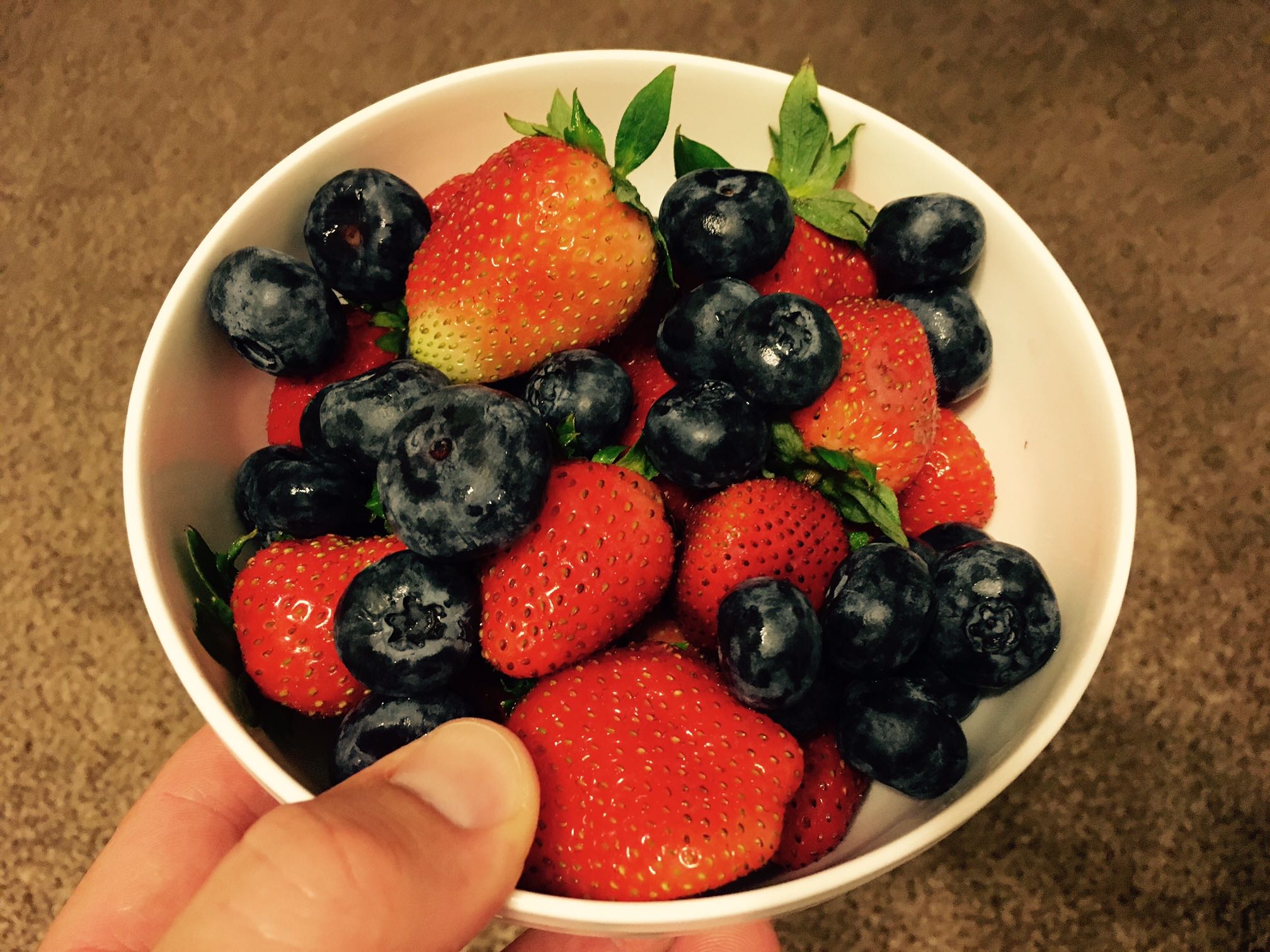 Plant-based bodybuilding champ Robert Cheeke holds a bowl of mixed berries, including blueberries and strawberries
