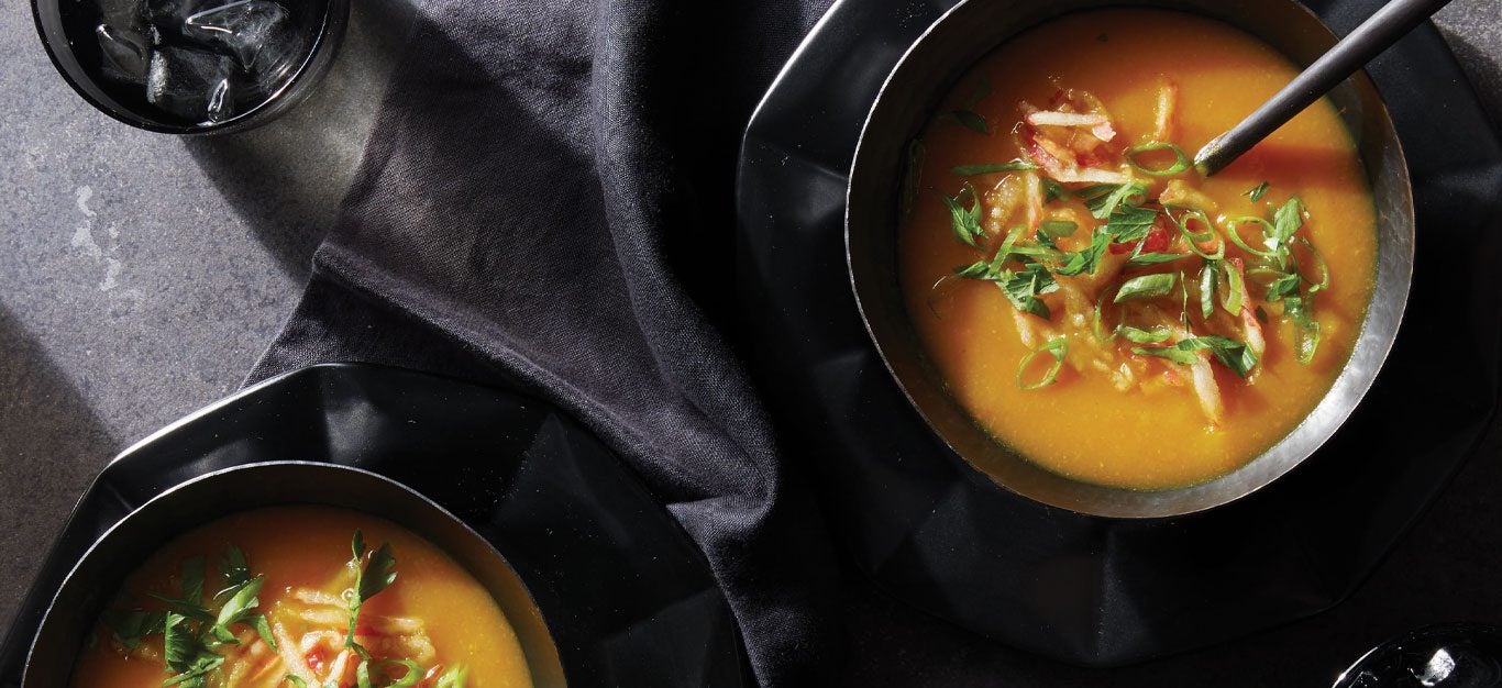 Instant Pot Golden Root Vegetable Soup in black bowls topped with chopped apple and scallions