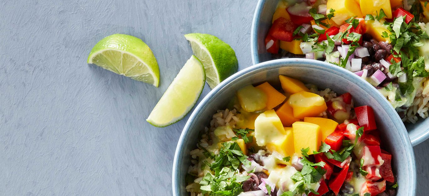 Mango Rice Salad Bowls in blue ceramic bowls with a side of lime wedges on a gray countertop