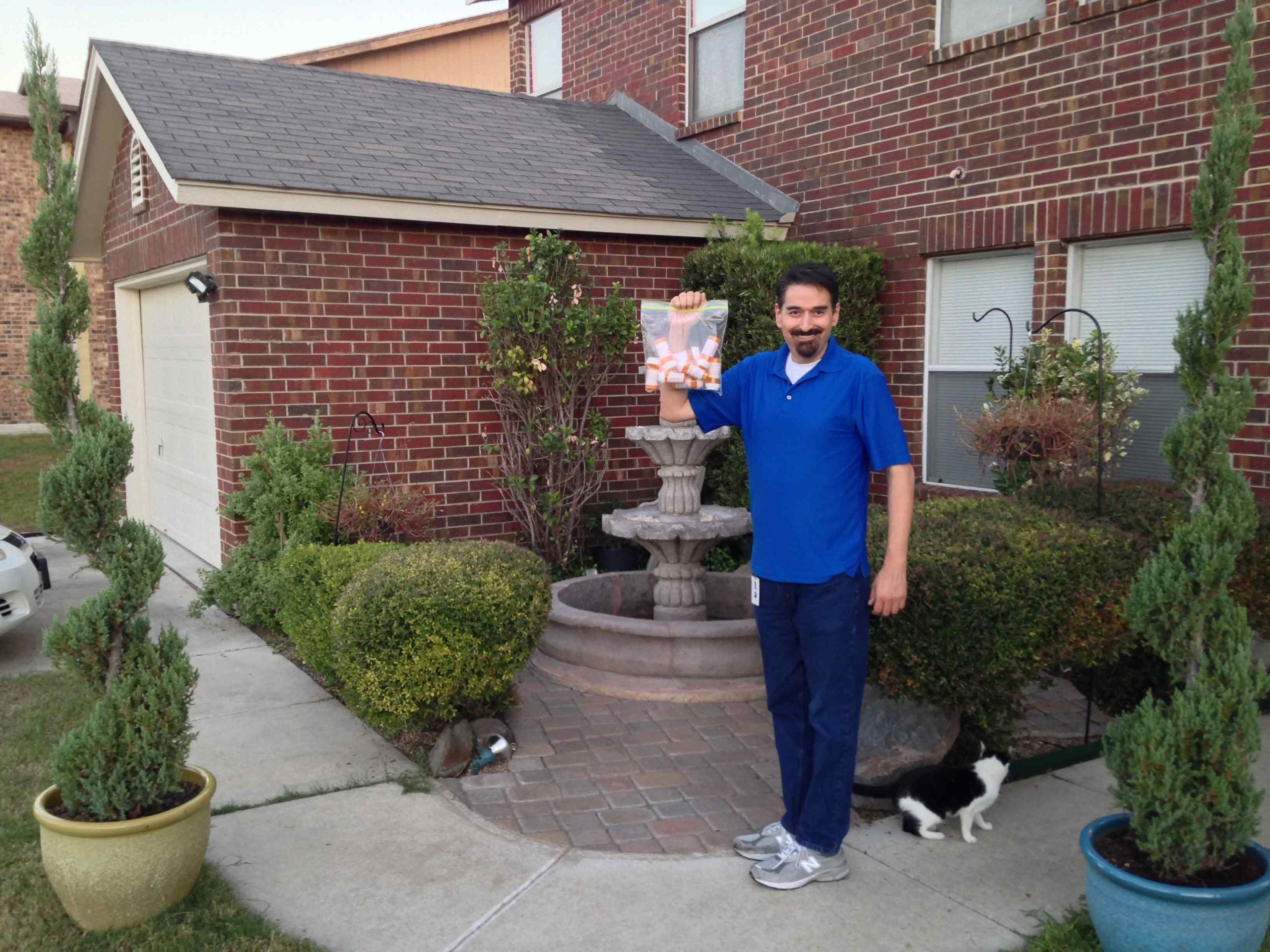 Mark Pro standing out front of his house holding a bag of medications that he was able to discontinue after adopting a plant-based diet
