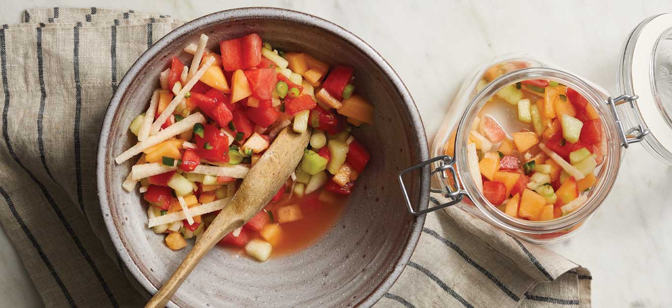 Summer Fruit Salsa with Melons and Jicama in a gray bowl on a striped dishcloth