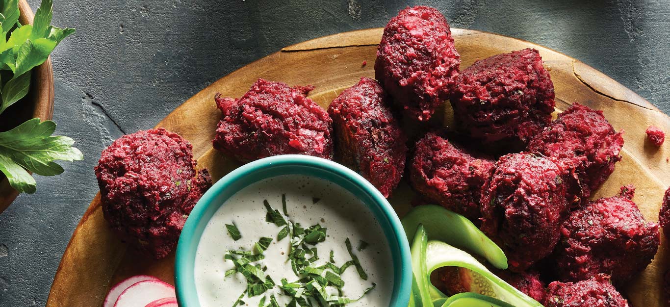 Roasted Beet Falafel with Chile-Lime Tahini Sauce on a round wooden platter