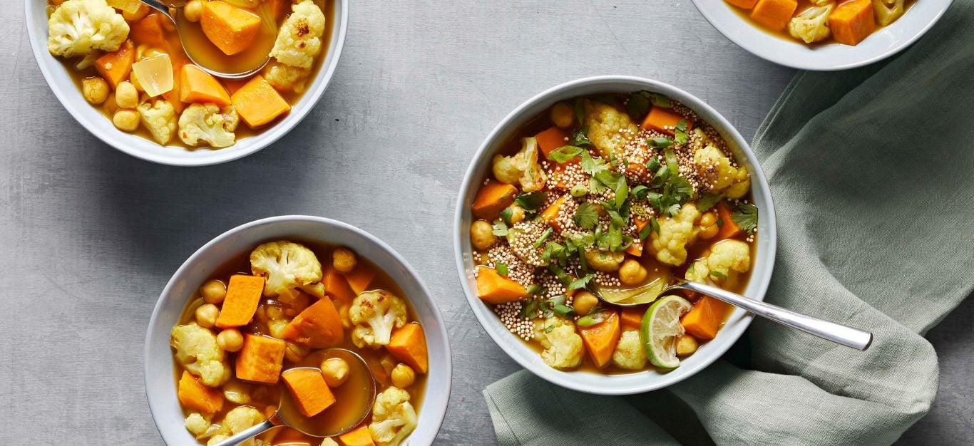 Roasted Cauliflower and Sweet Potato Soup in three bowls on a gray counter