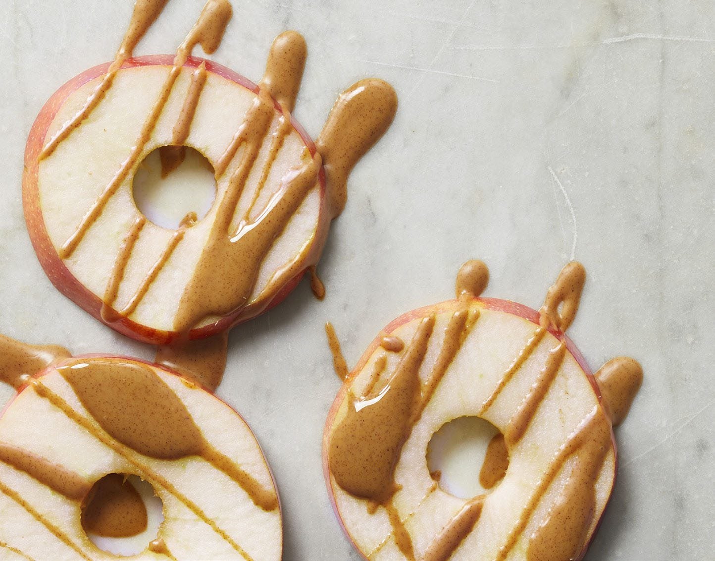 Round slices of apples drizzled with almond butter make a delicious and healthy plant-based snack