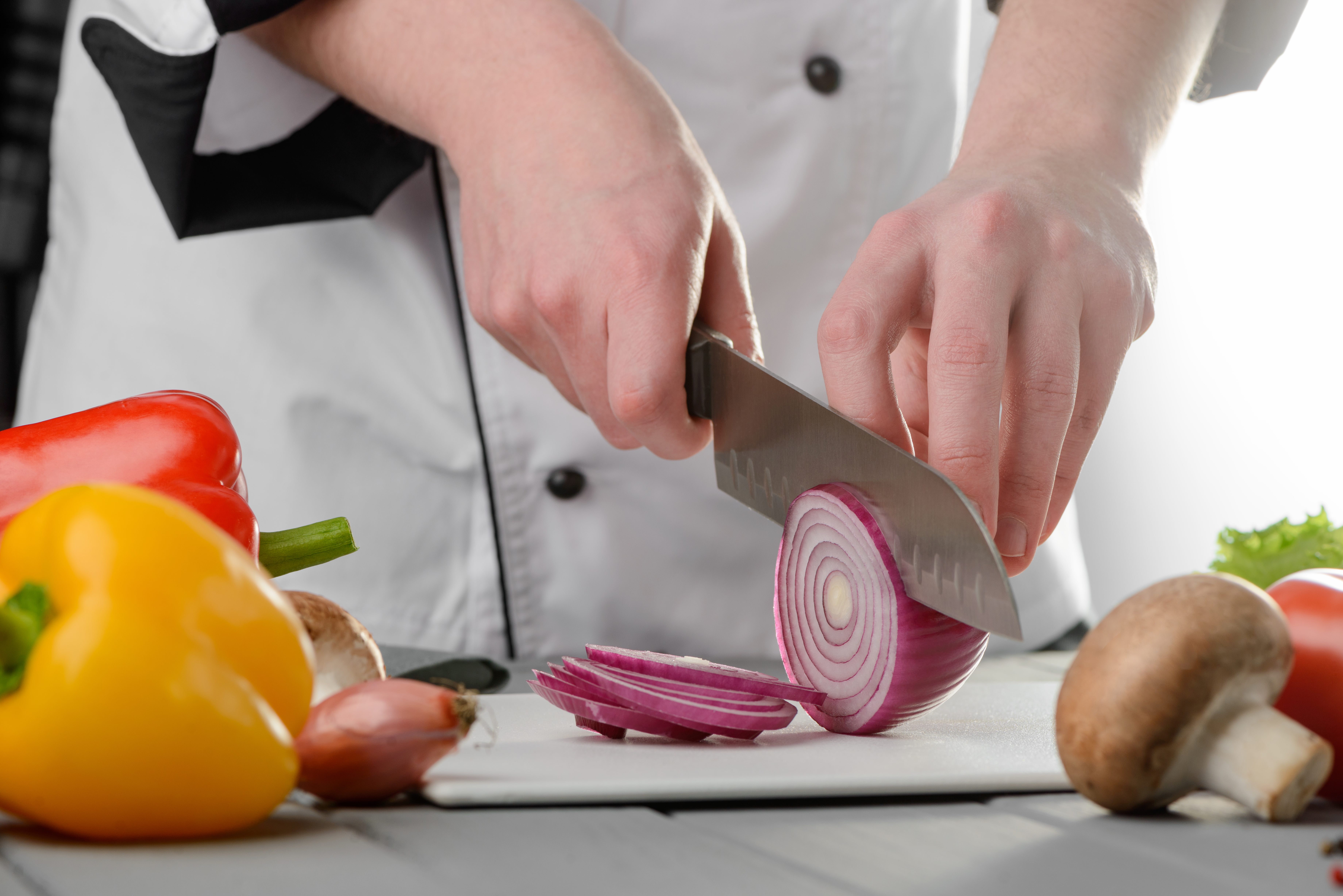 Professional chef cutting red onion