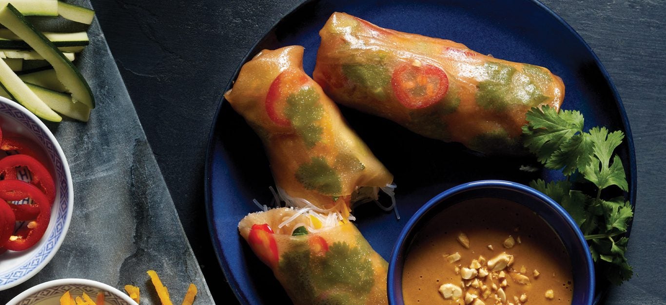 Squash and Bean Thread Noodle Spring Rolls on a blue plate with peanut sauce