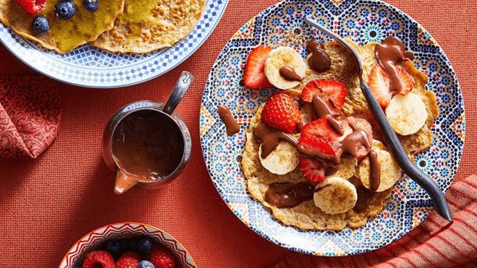 Pancakes topped with strawberries, banana slices, and chocolate sauce