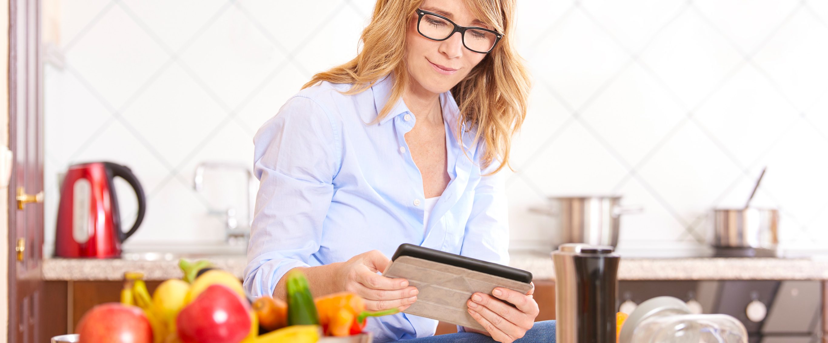 Woman Reading Tablet in Kitchen With Vegetables