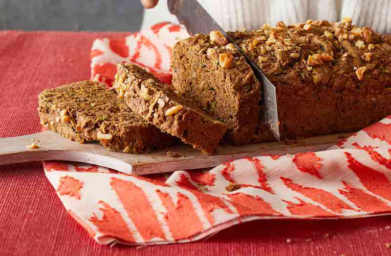 Zucchini bread sliced ​​on cutting board above red cloth on red table