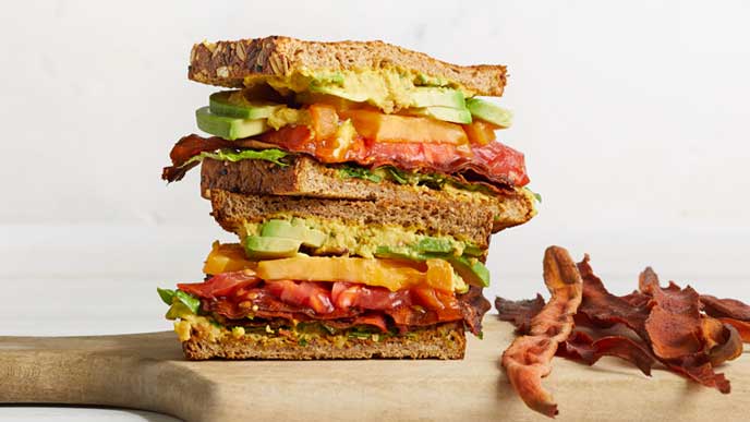 Vegan BLTA with Carrot Bacon on wooden cutting board