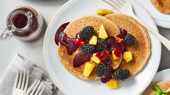 Double Blackberry and Pineapple pancakes on a white plate