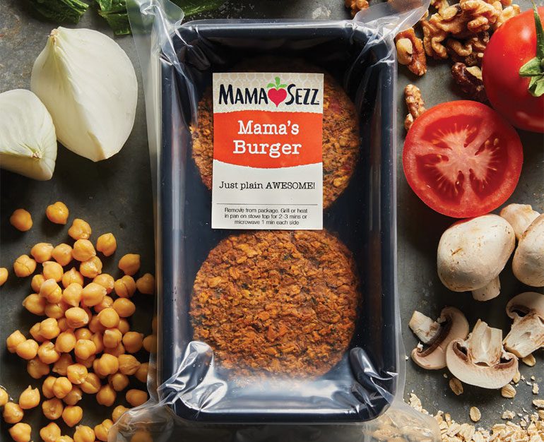 Mama Sezz burger in plastuc packaging surrounded by chickpeas, mushrooms, tomatoes, and onion