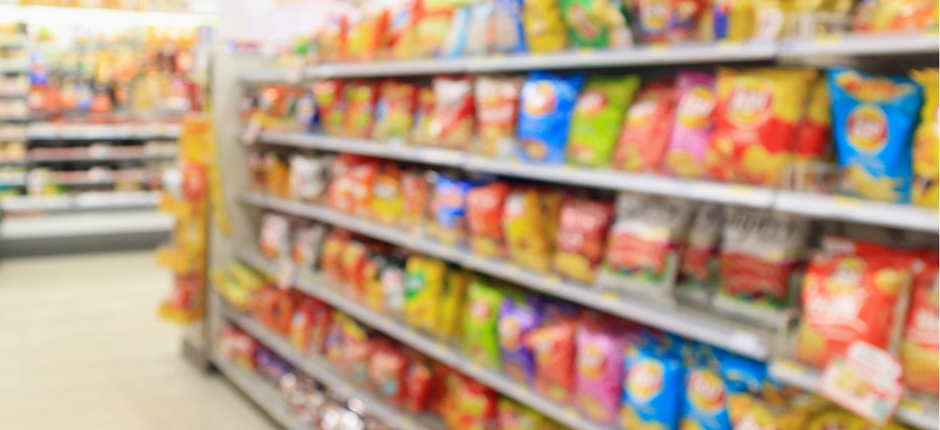 Grocery store aisle with chips and highly processed foods, blurred