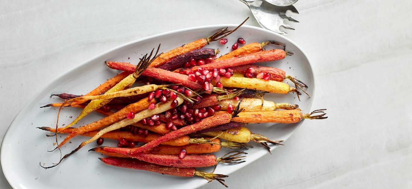 Cardamom Roasted Carrots with Pomegranate Seeds on a white serving dish