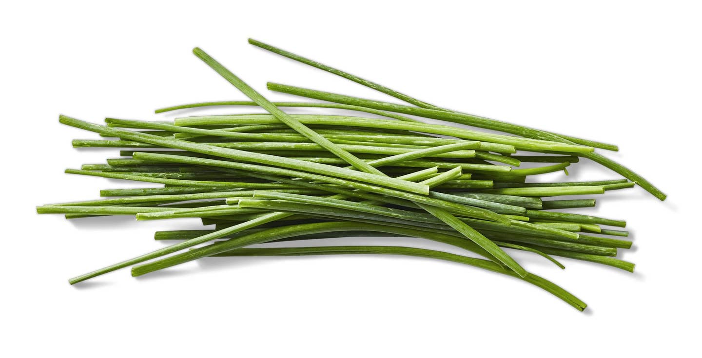 A bunch of trimmed green chives on a white background
