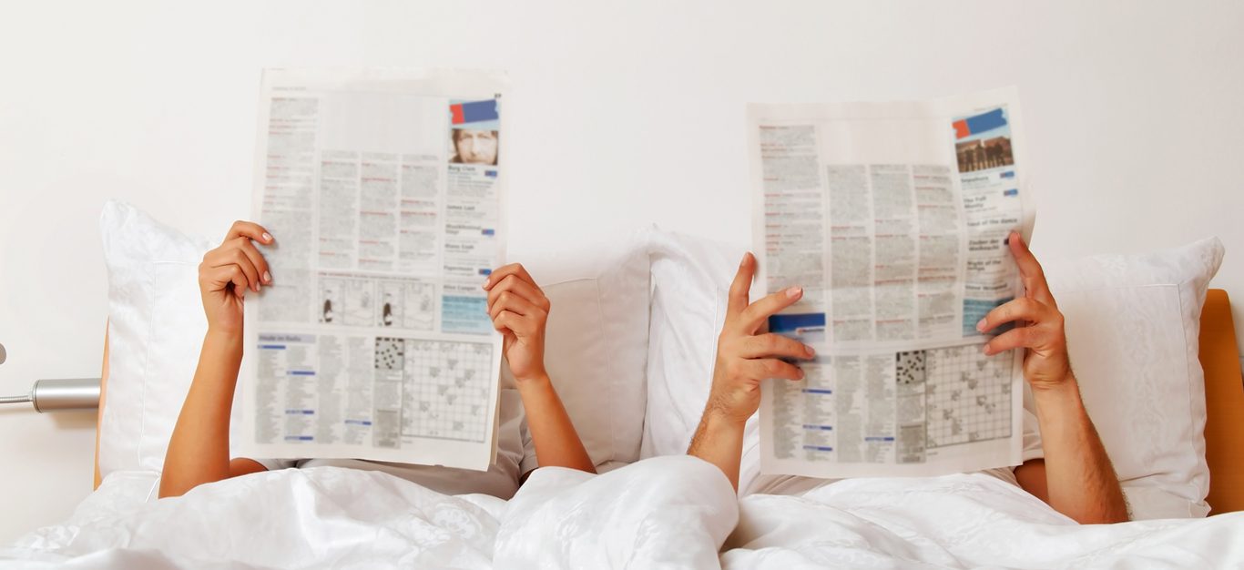 Erectile dysfunction - couple reads newspaper in bed