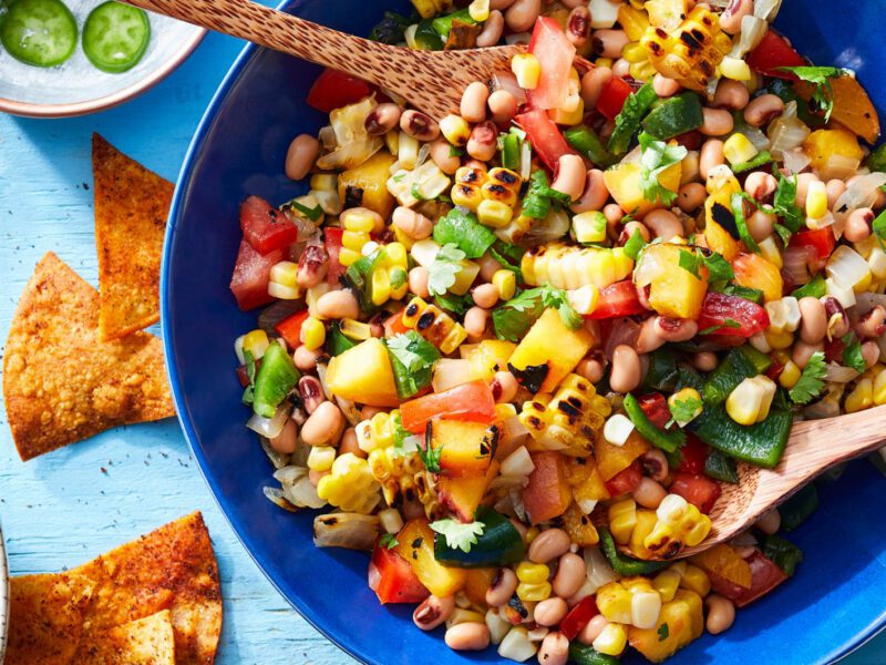 Peach-Corn Salsa in a large bright blue bowl with Chili-Lime Chips in another bowl to the side