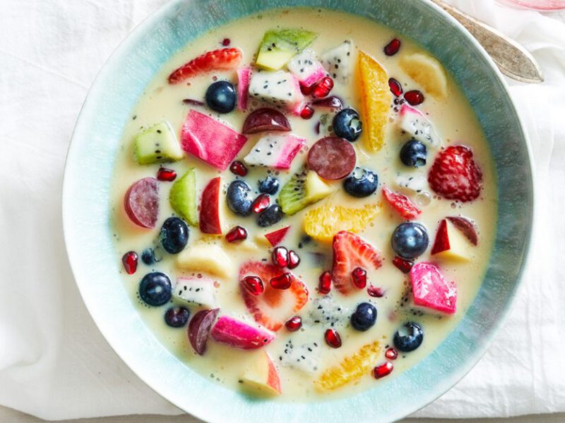 A bowl of Mixed Fruit Soup filled with fresh strawberries, orange slices, blueberries, and other fruits