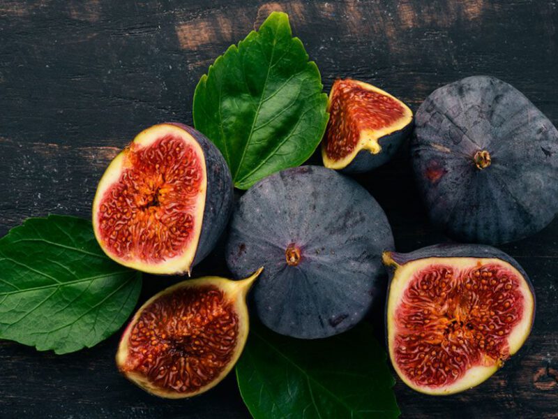 Figs - whole and cut with some leaves on black background