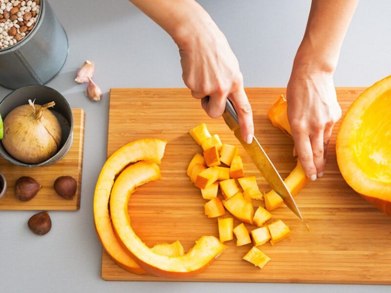 Woman cutting pumpkins on a cutting board, preparing to cook