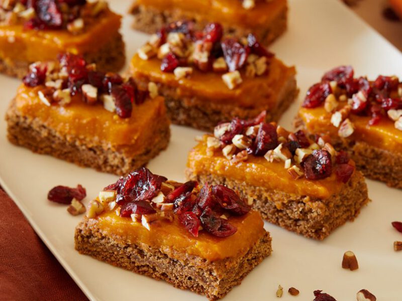 A white serving platter with Almond-Oat Cookie Bars with Pumpkin Frosting, spaced so there is room between each piece