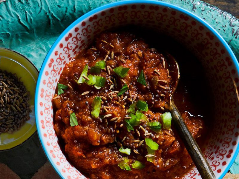 Bold red tomato chutney served in a teal stoneware bowl