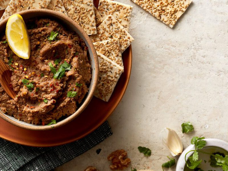 lentil-walnut vegan pate served with crackers and garnished with herbs