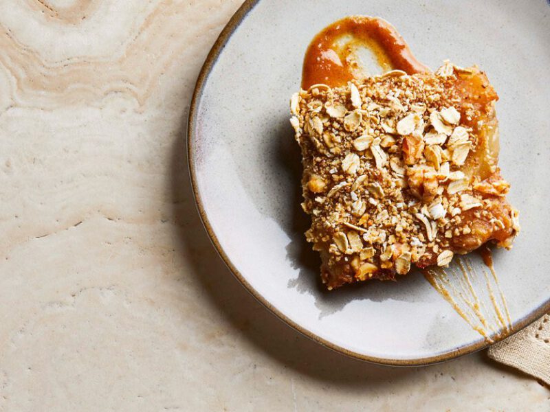 Vegan apple pie bar shown with a drizzling of cider glaze on a white dessert plate