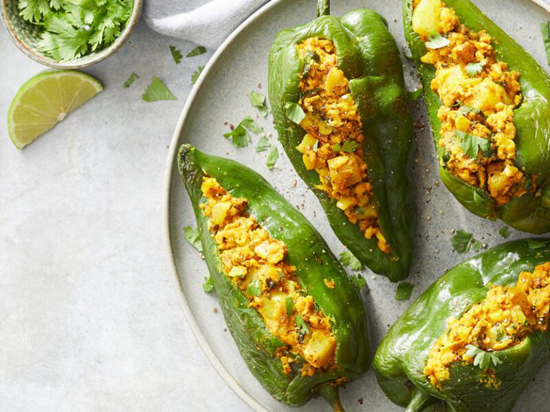 Vegan Indian-Spiced Stuffed Poblano Peppers - Four stuffed green poblano peppers on a white plate and white table