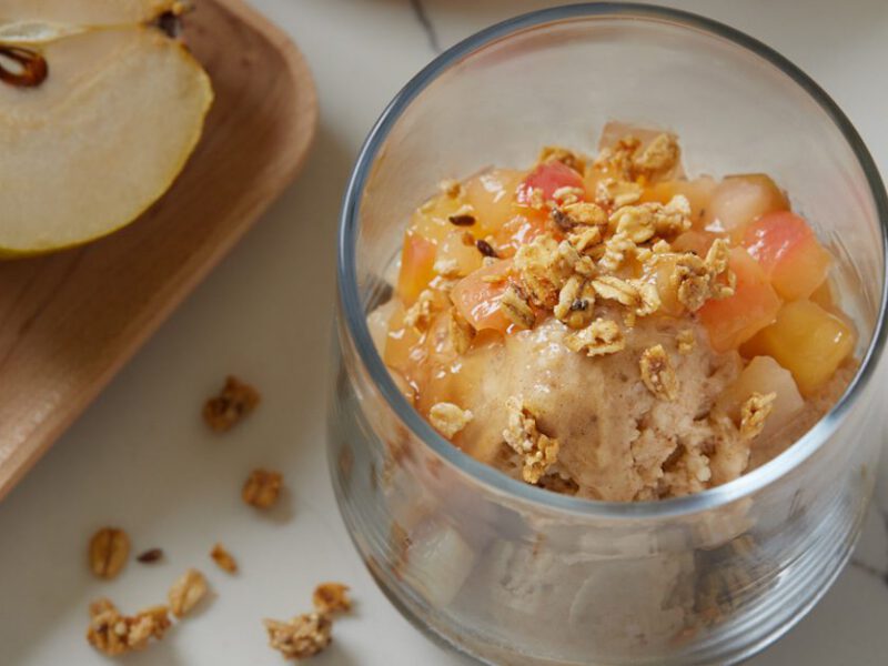 cinnamon banana nice cream - fruity, dairy-free ice cream shown in a glass cup topped with chopped, cooked-down pears