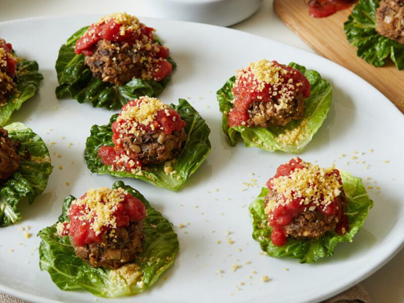 Half a dozen Fancy Vegan Meatballs served in small lettuce boats on a large white platter