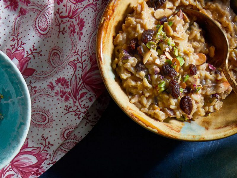Brown rice kheer in a bowl garnished with raisins and pistachios