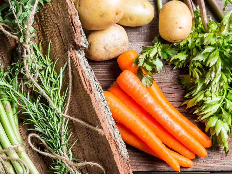 Spring vegetables on wooden background - asparagus carrots and herbs