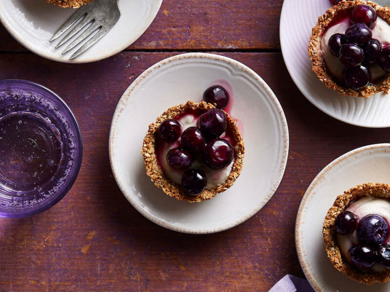 Mini tarts shown on individual plates - small tartlets with a lavender-vanilla filling and saucy blueberry topping