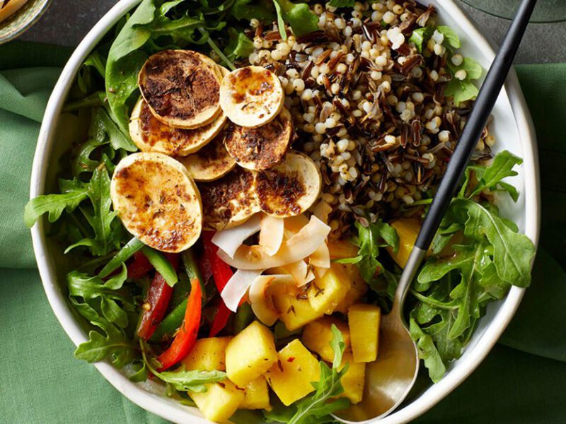 Colorful grain bowls with greens and sliced, crispy plantain chips, seasoned with jerk spices