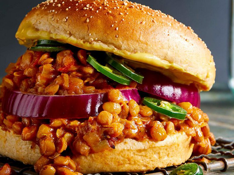 Close-up shot of a lentil sloppy joe with filling spilling out of bun